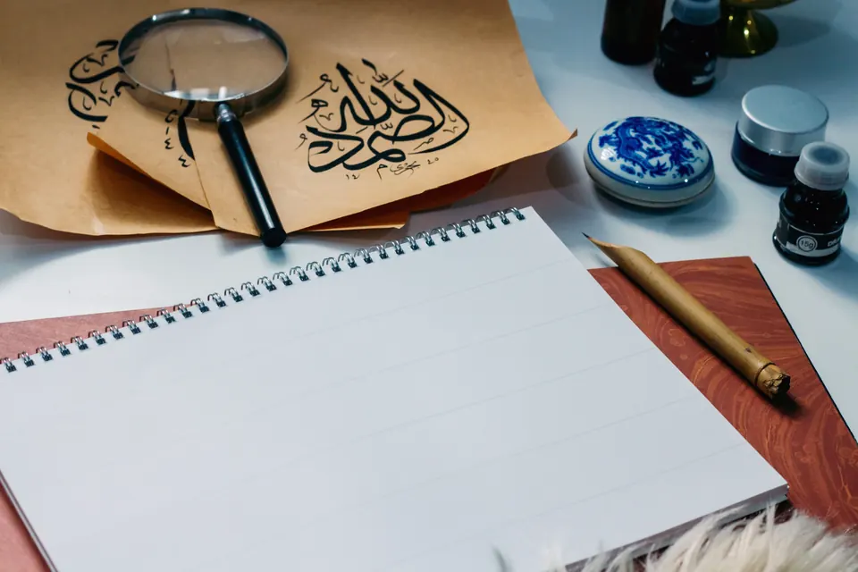 Arabic calligraphy practice with a reed pen, ink, and handwritten script