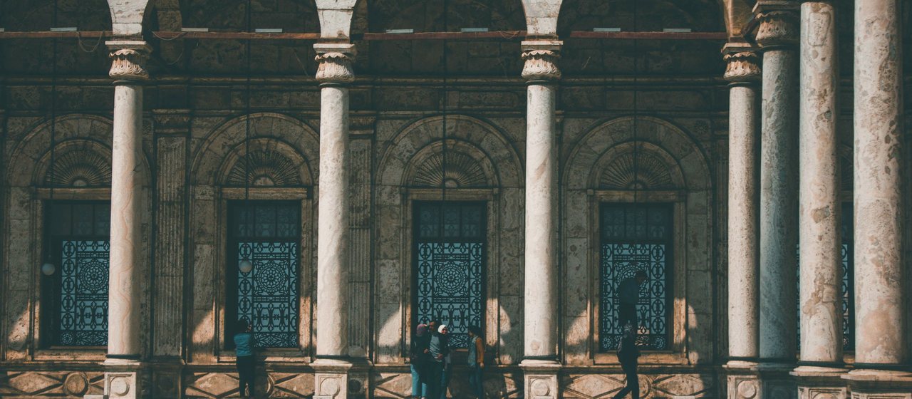 Sunlit stone arches of a historic mosque courtyard